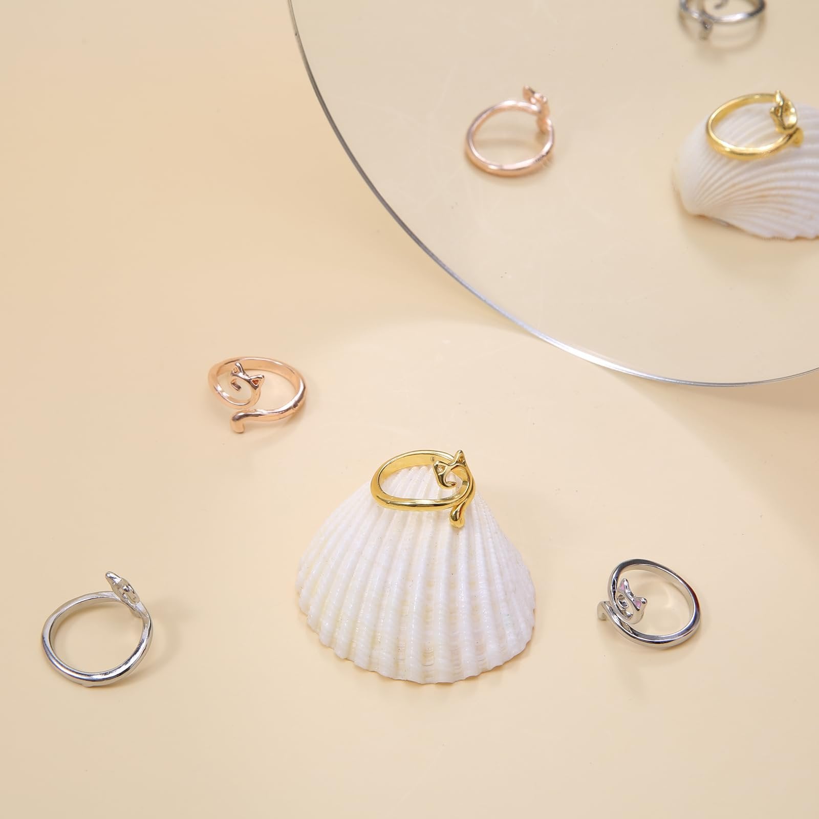 Assortment of adjustable metal crochet rings with cat designs, in gold, rose gold, and silver tones, displayed on seashells.