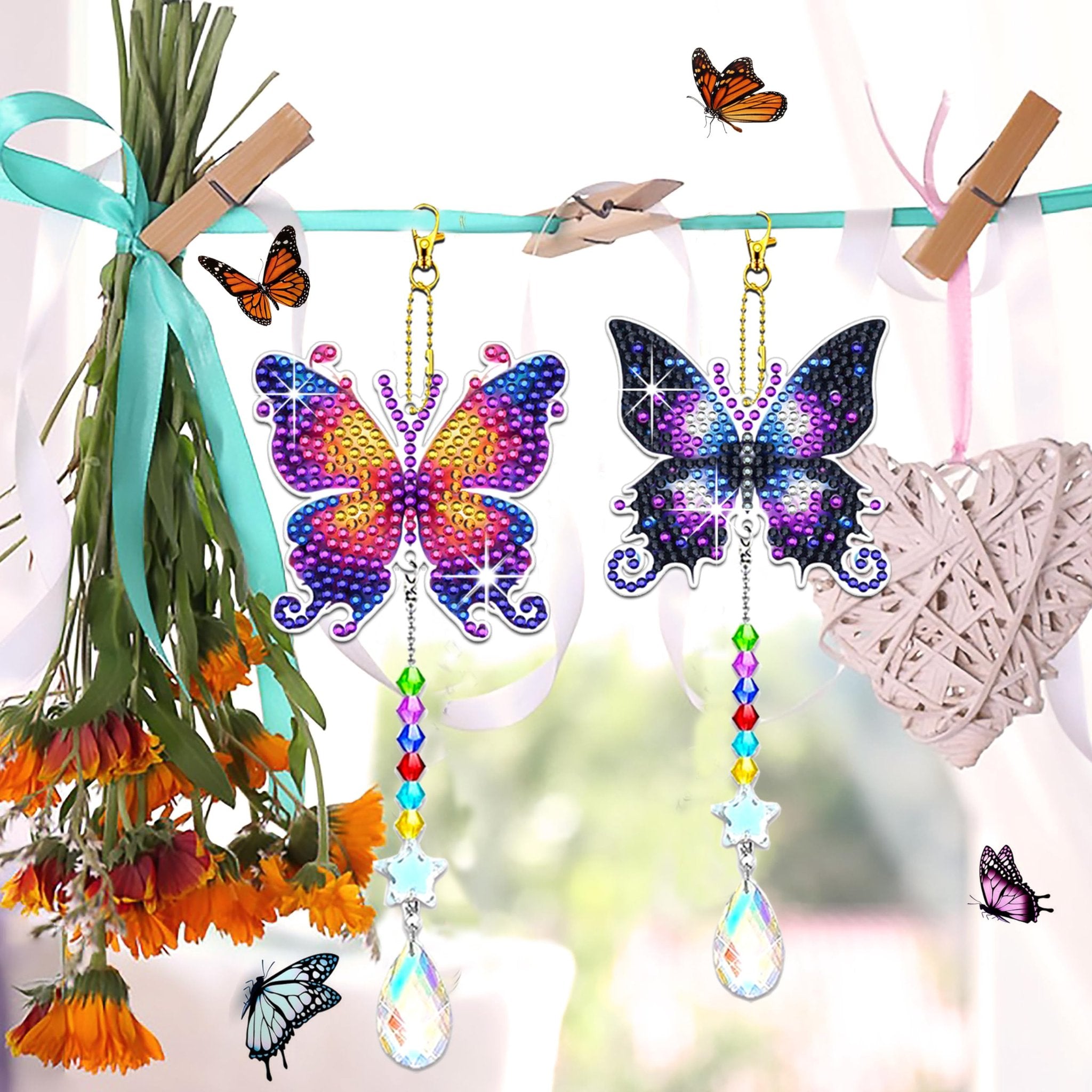 Two diamond art butterfly suncatchers hanging on a line with colorful beads and crystals, next to flowers and a woven heart decoration.