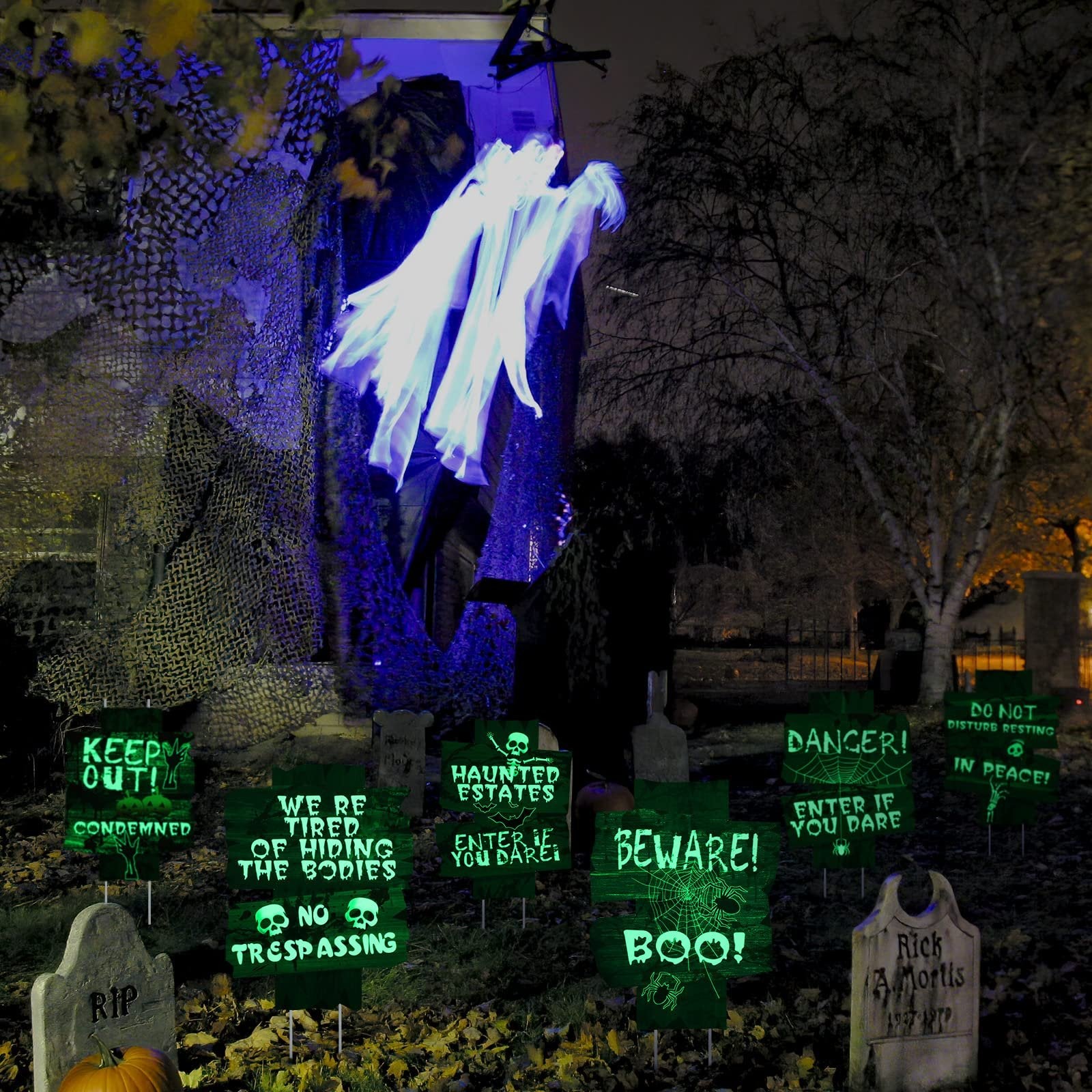 Halloween yard signs with spooky messages and glowing ghosts in a yard at night