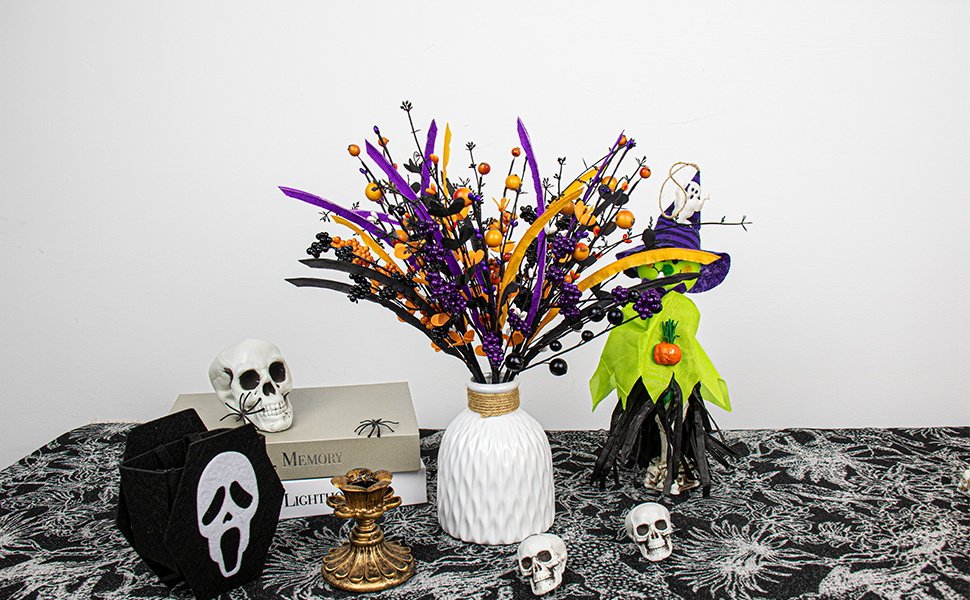 Halloween floral arrangement with black stems, purple and orange berries, and a witch figure in a vase on a patterned tablecloth.