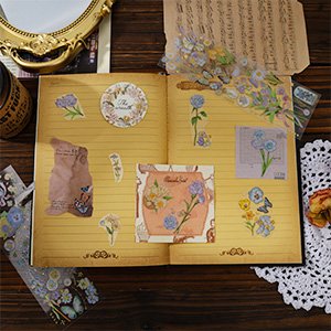 Open notebook with vintage floral stickers and dried flowers arranged on pages.
