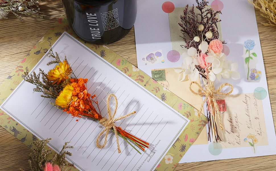 Two small bouquets of dried flowers tied with twine, arranged on stationery with decorative stickers and a dark mug.