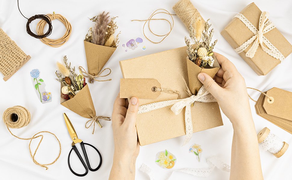 Hands arranging dried flower bouquets and craft supplies for DIY gift wrapping