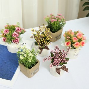 Six artificial flower arrangements in ceramic pots on a white surface, featuring pink, yellow, and white blossoms.