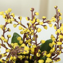 Close-up of yellow faux berries on brown stems with green leaves, part of an artificial floral arrangement.