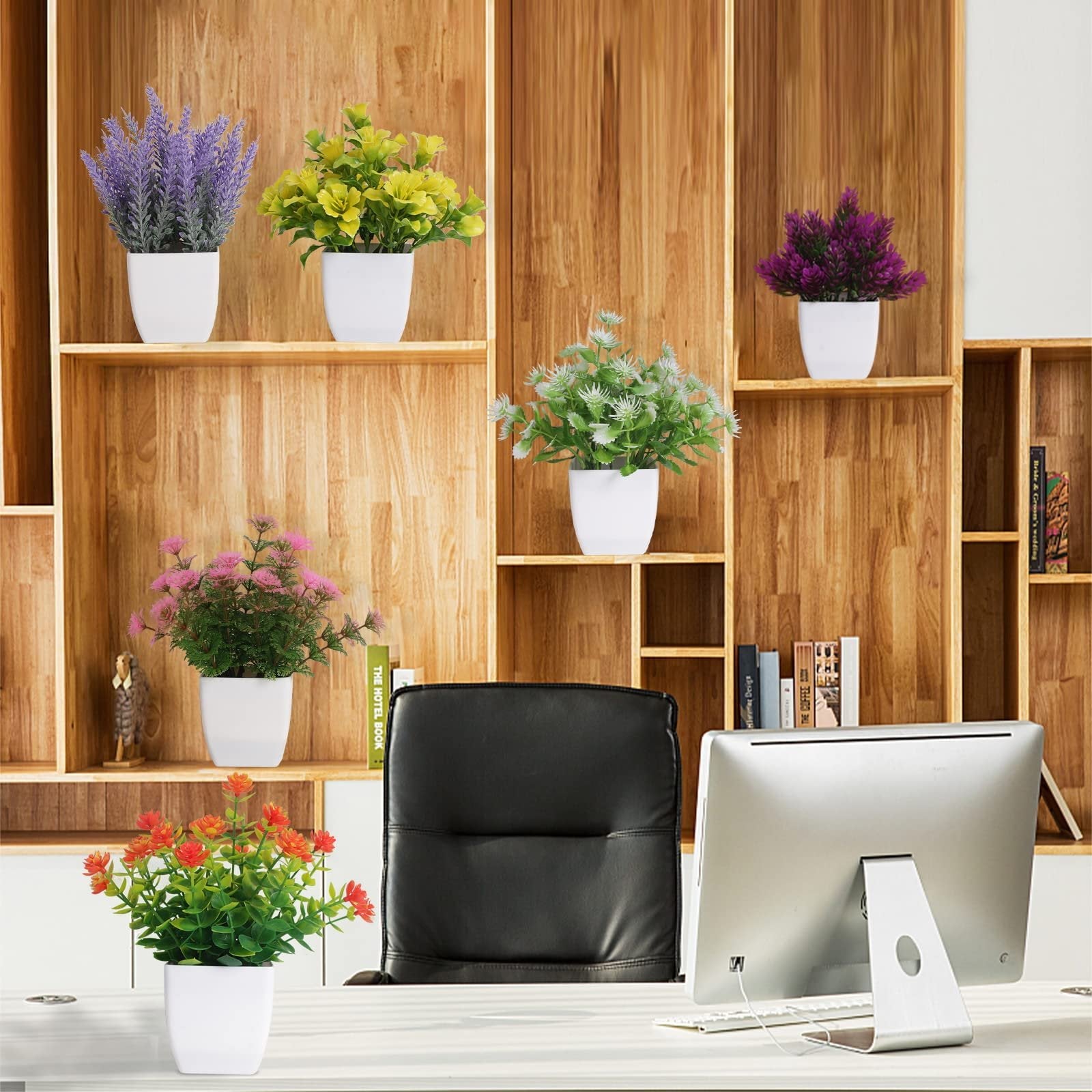 Six artificial potted plants arranged on wooden shelves and a desk, including lavender, yellow, purple, white, pink, and orange flowers.
