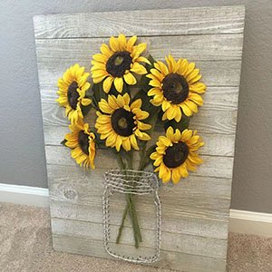 Artificial sunflowers arranged in a mason jar design on a wood plank background