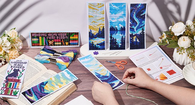 Cross stitch bookmark kit contents including floss, needles, instructions, and several finished bookmarks with landscape and book-themed designs.