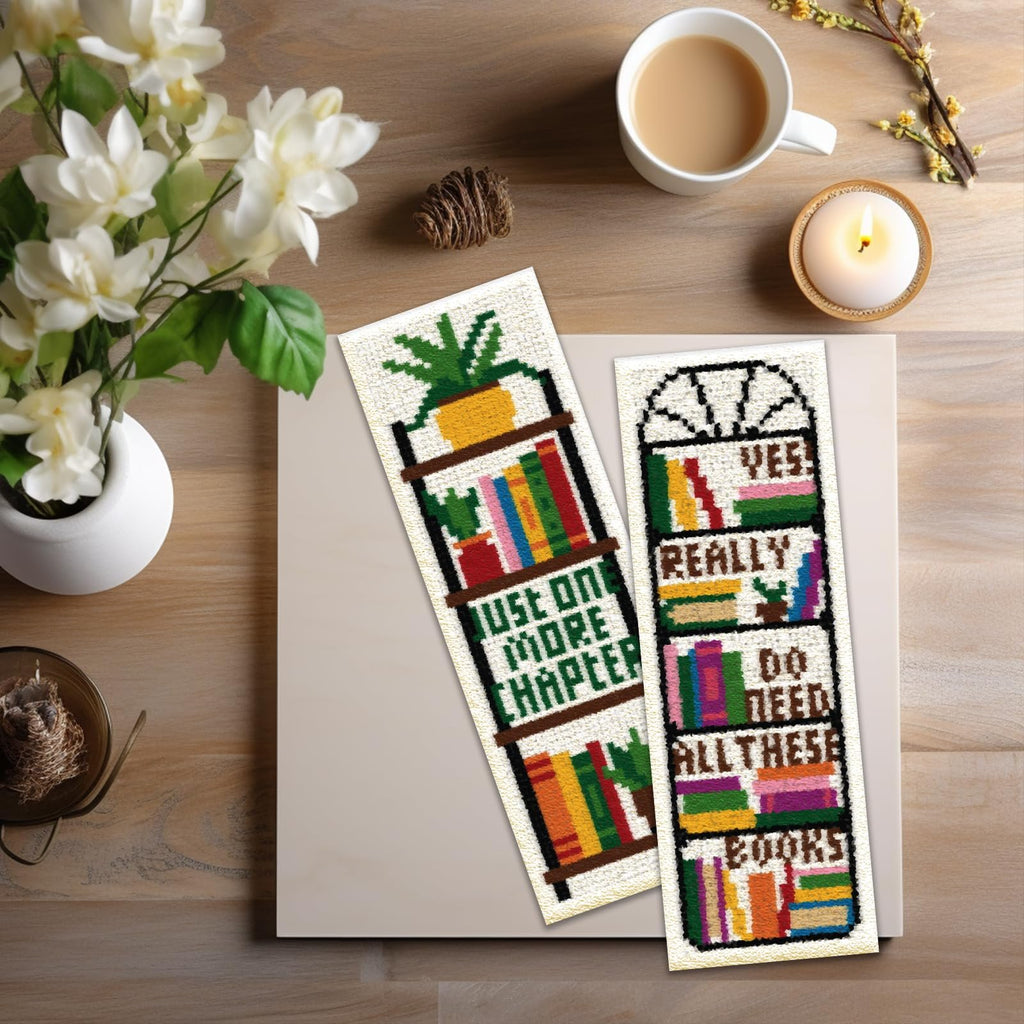 Two cross stitch bookmarks with bookshelf designs, one says 'Just One More Chapter', the other says 'Yes Really Do Need All These Books'.