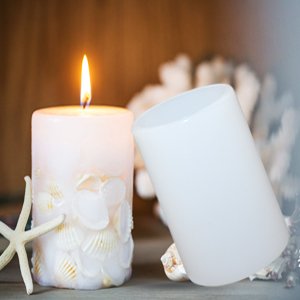 White cylindrical silicone mold next to a decorated candle with seashells and a starfish.