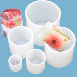 Set of six graduated white silicone cylinder molds for crafts, one with red flowers inside, one with a floral decal.
