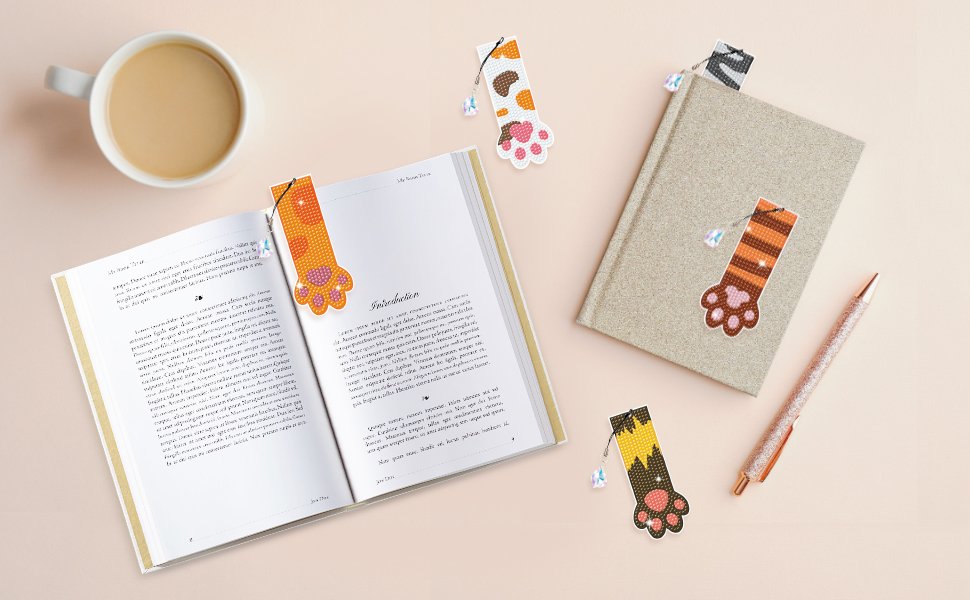 Diamond painting cat paw bookmarks with crystal pendants on open book and notebook