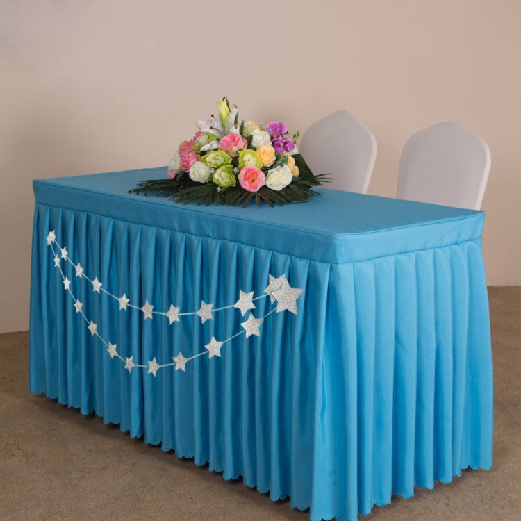 Blue table skirt with a double string of silver glitter stars draped across the front, topped with a floral arrangement.