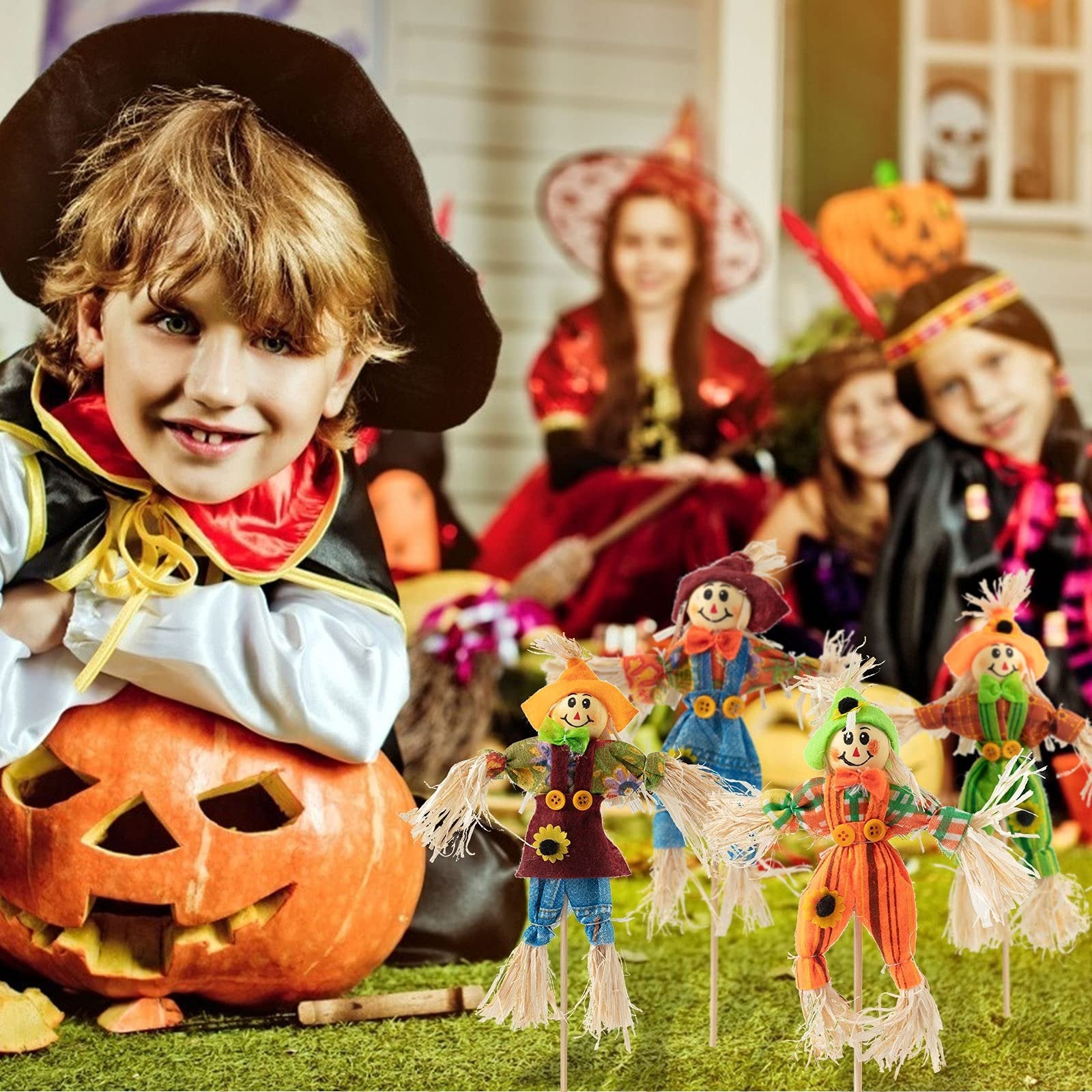 Children in Halloween costumes with scarecrow decorations and a carved pumpkin on grass