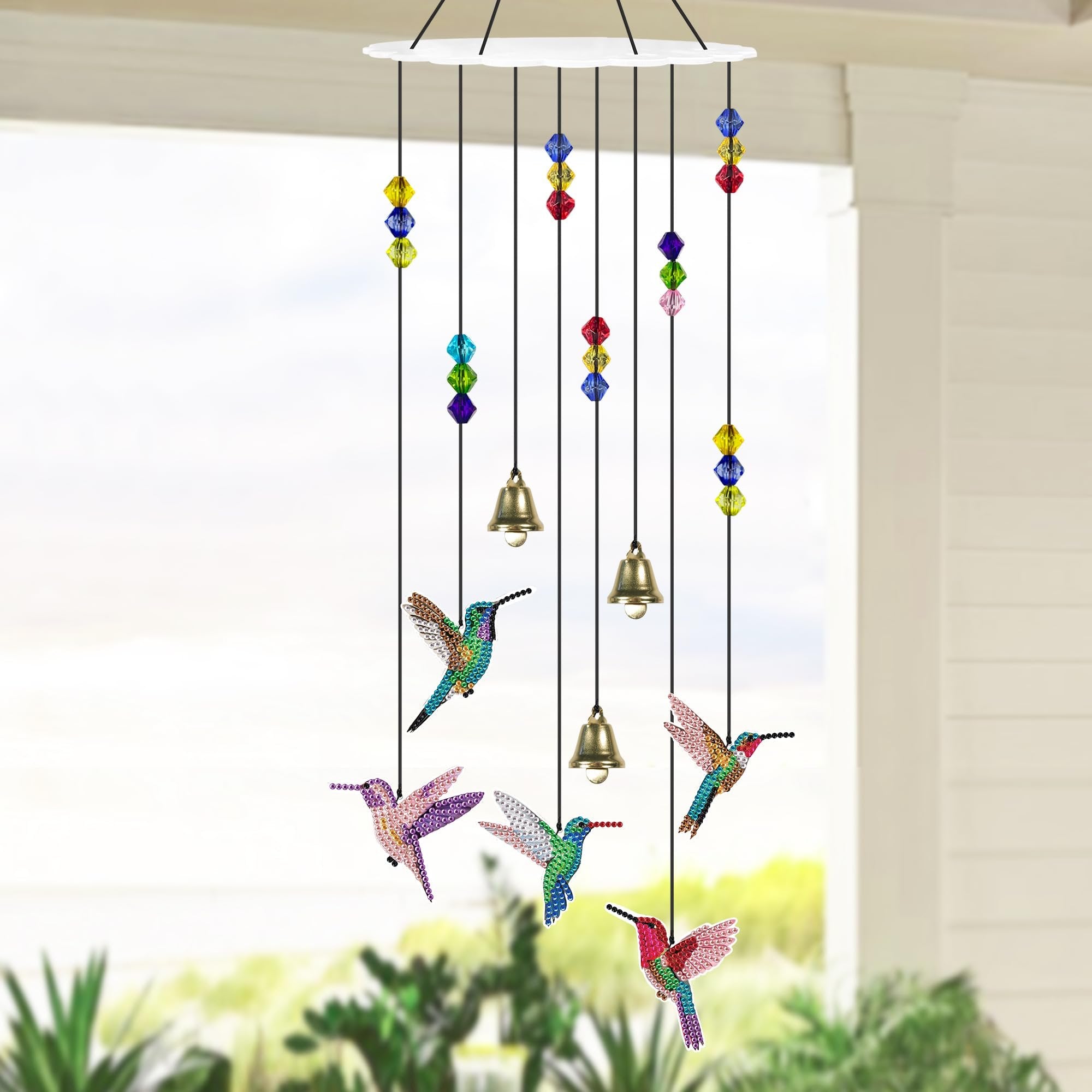 Diamond painting hummingbird wind chime with colorful beads and bells hanging outdoors