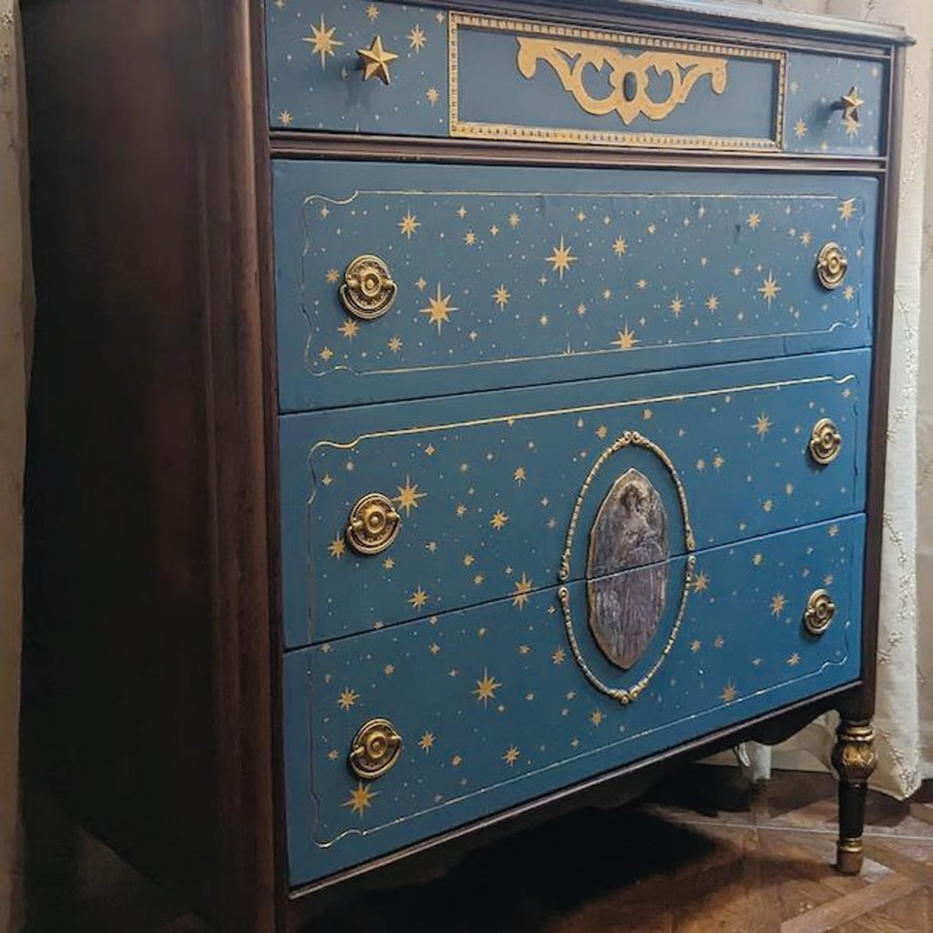 Blue dresser with gold star pattern and ornate drawer pulls, angled view.
