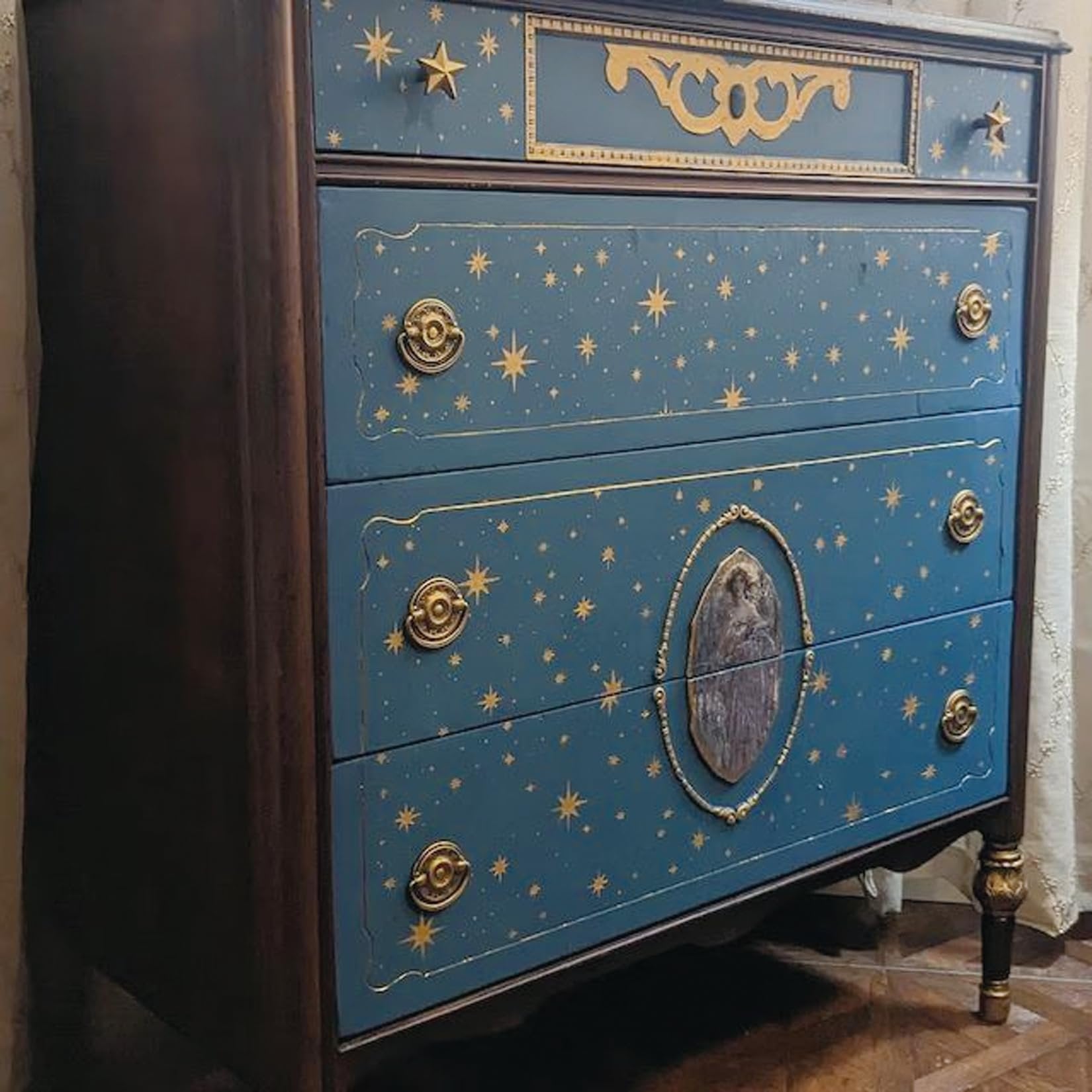 Blue dresser with gold star pattern and ornate drawer pulls, angled view.