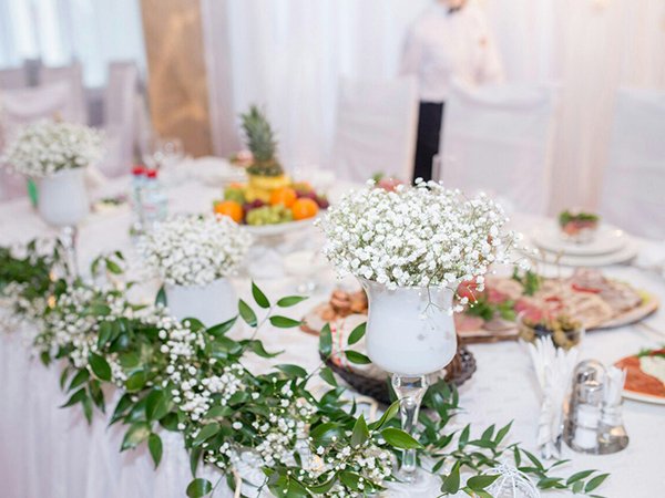 White baby's breath floral arrangements and greenery on a decorated table at a formal event