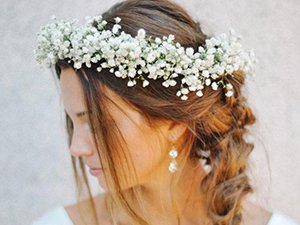 Woman wearing a white baby's breath flower crown with braided hair and earrings