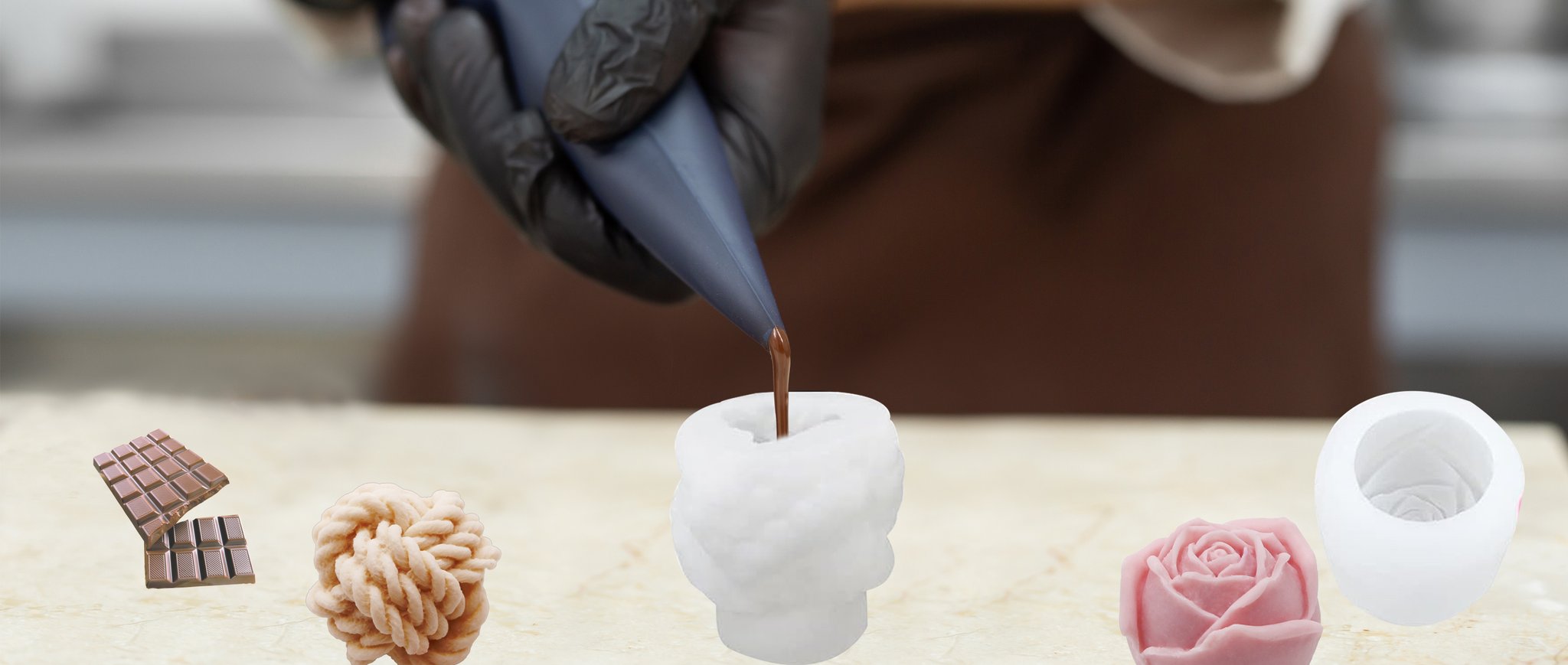 Silicone candle molds with chocolate bars, a textured sphere, and a rose shape, as chocolate is piped into a mold.