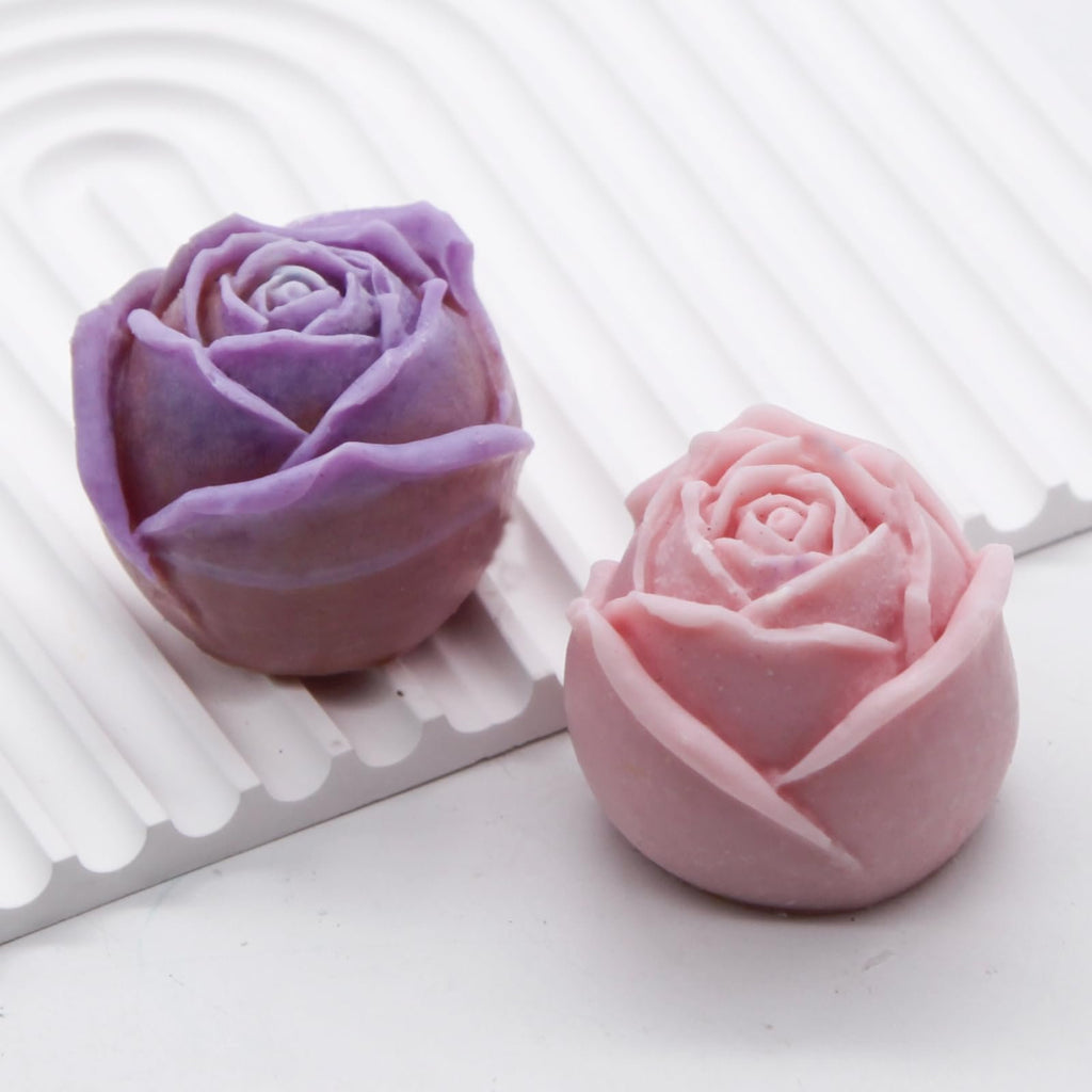 Two rose-shaped silicone molds, one purple and one pink, displayed on a white textured surface.