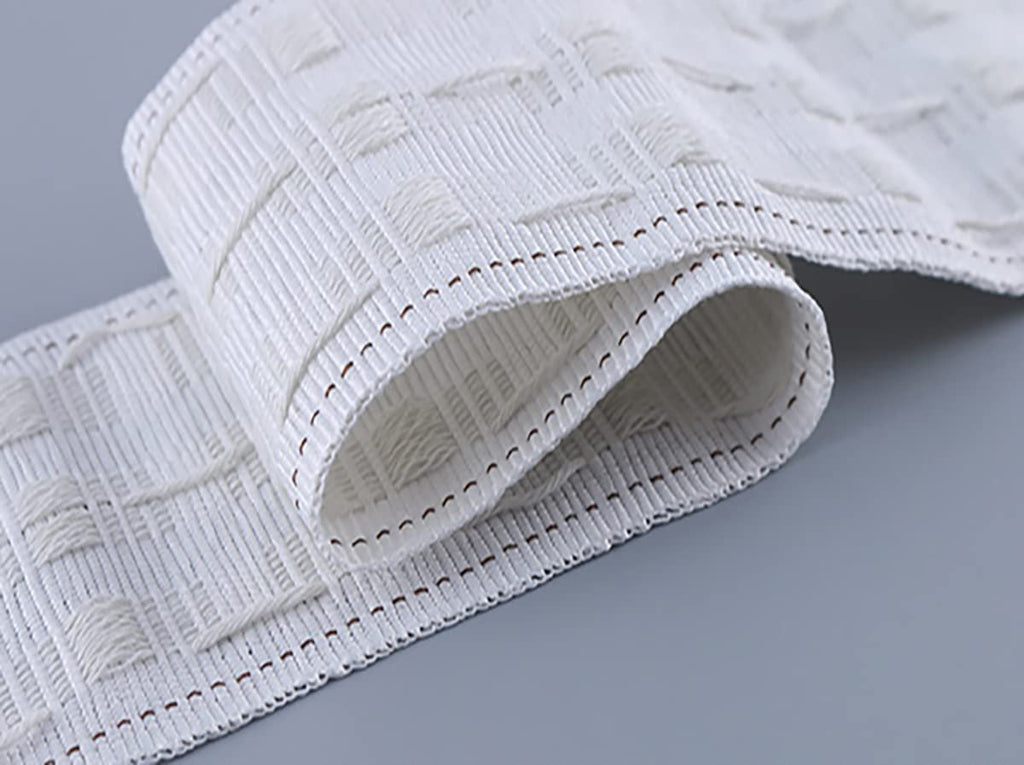 White curtain pleating tape with a woven square pattern and visible stitching along the edges, shown rolled and angled on a gray surface.
