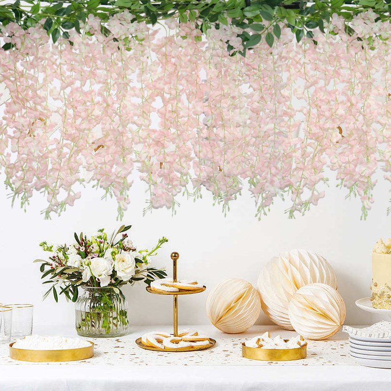 Pink wisteria garland draped above a table setting with flowers, cookies, and decorative spheres.