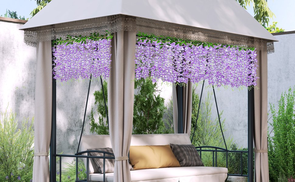 Four strands of artificial pink wisteria garlands hanging from a gazebo roof over a swing set with cushions.