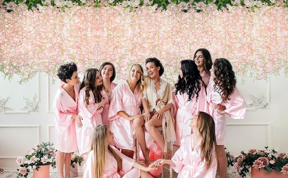 Group of women in pink robes posing for a photo with a backdrop of pink wisteria flowers