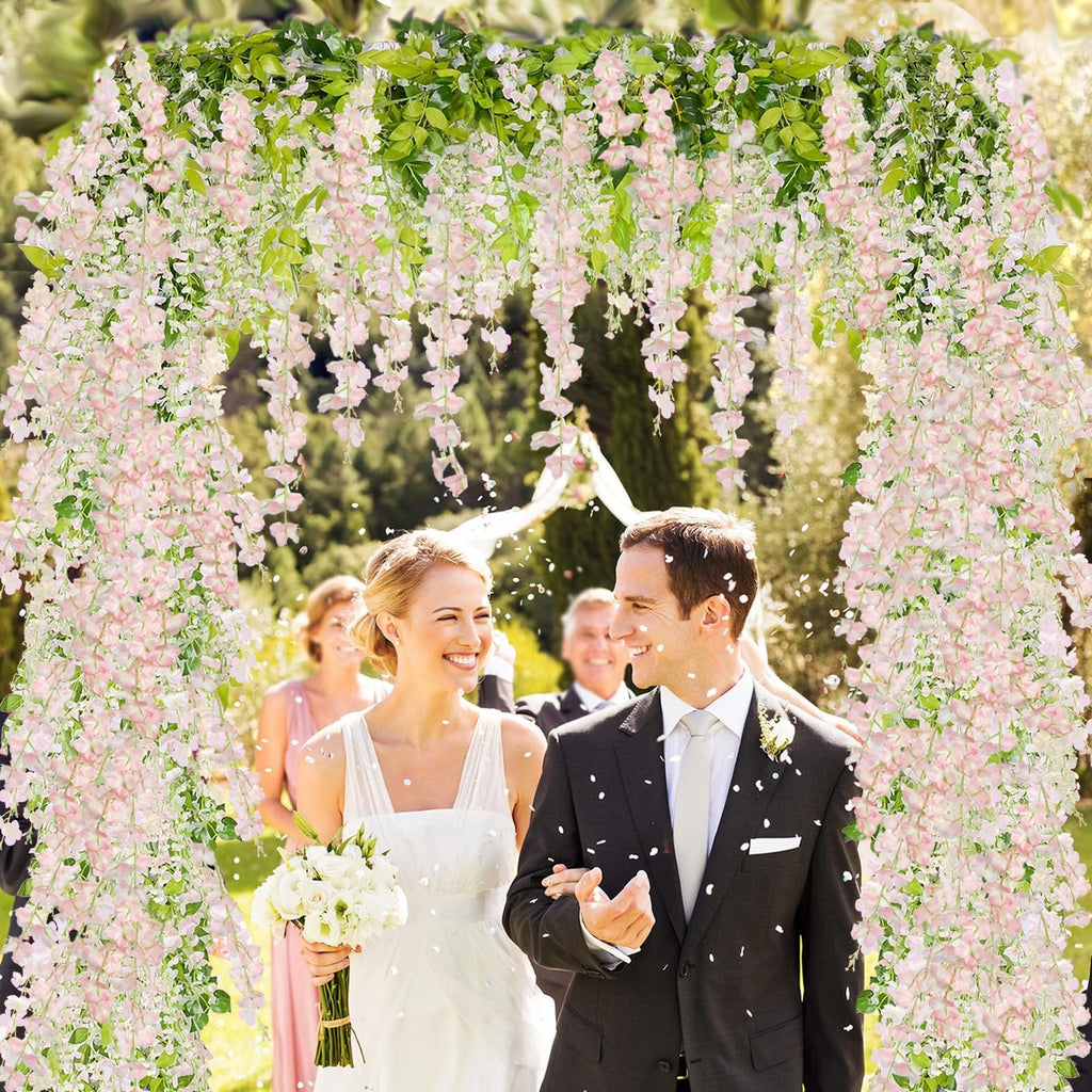 Newlyweds walking under a pink wisteria archway with confetti falling