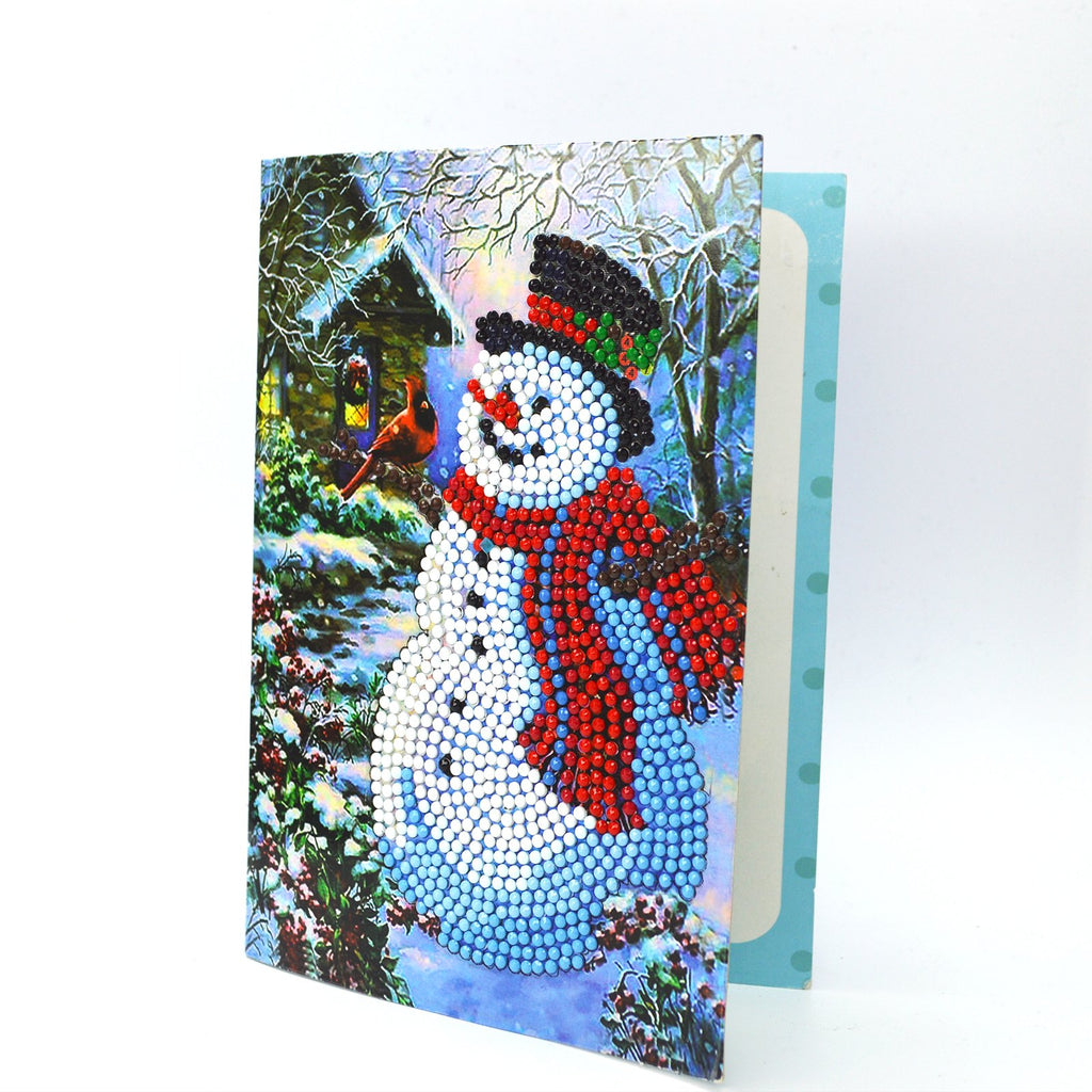 Diamond painting card featuring a snowman with a cardinal in a snowy scene, partially open to show a light blue interior.