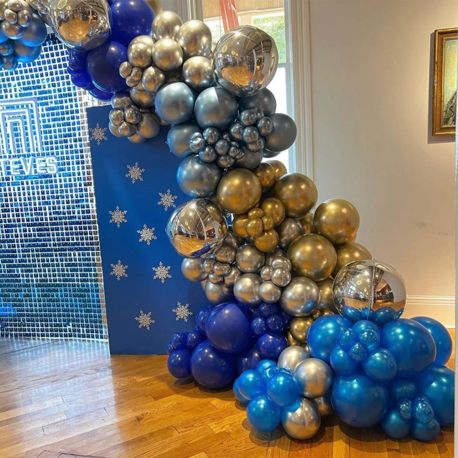 Balloon arch in navy blue, gold, and silver with snowflake decorations on a blue backdrop.