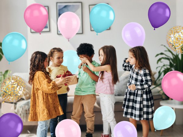 Children opening a gift surrounded by pastel and confetti balloons in a living room setting.