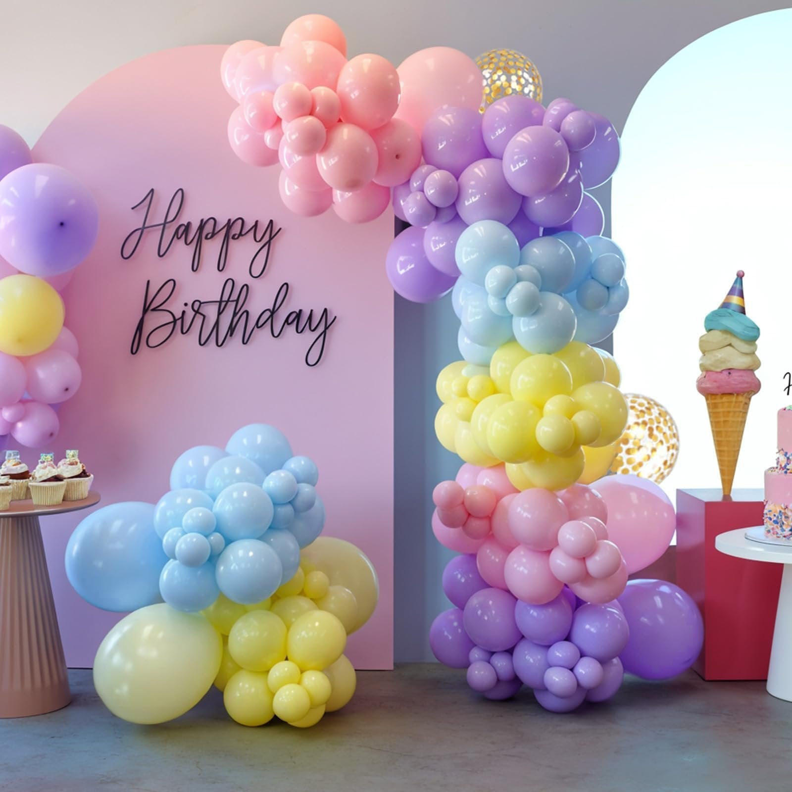 Pastel balloon garland arch and clusters in pink, purple, yellow, and blue, with 'Happy Birthday' text on a pink backdrop.
