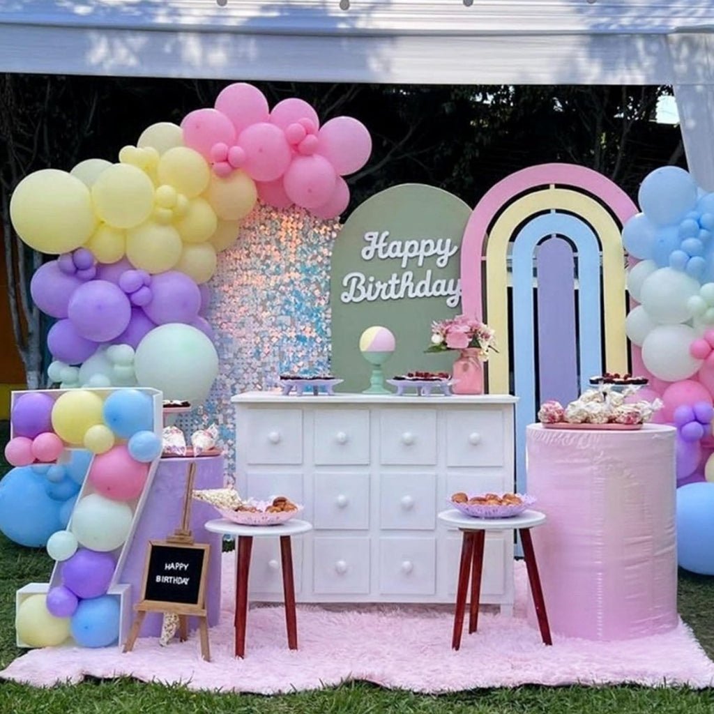 Birthday party setup with pastel balloons, a white dresser, and rainbow decorations.