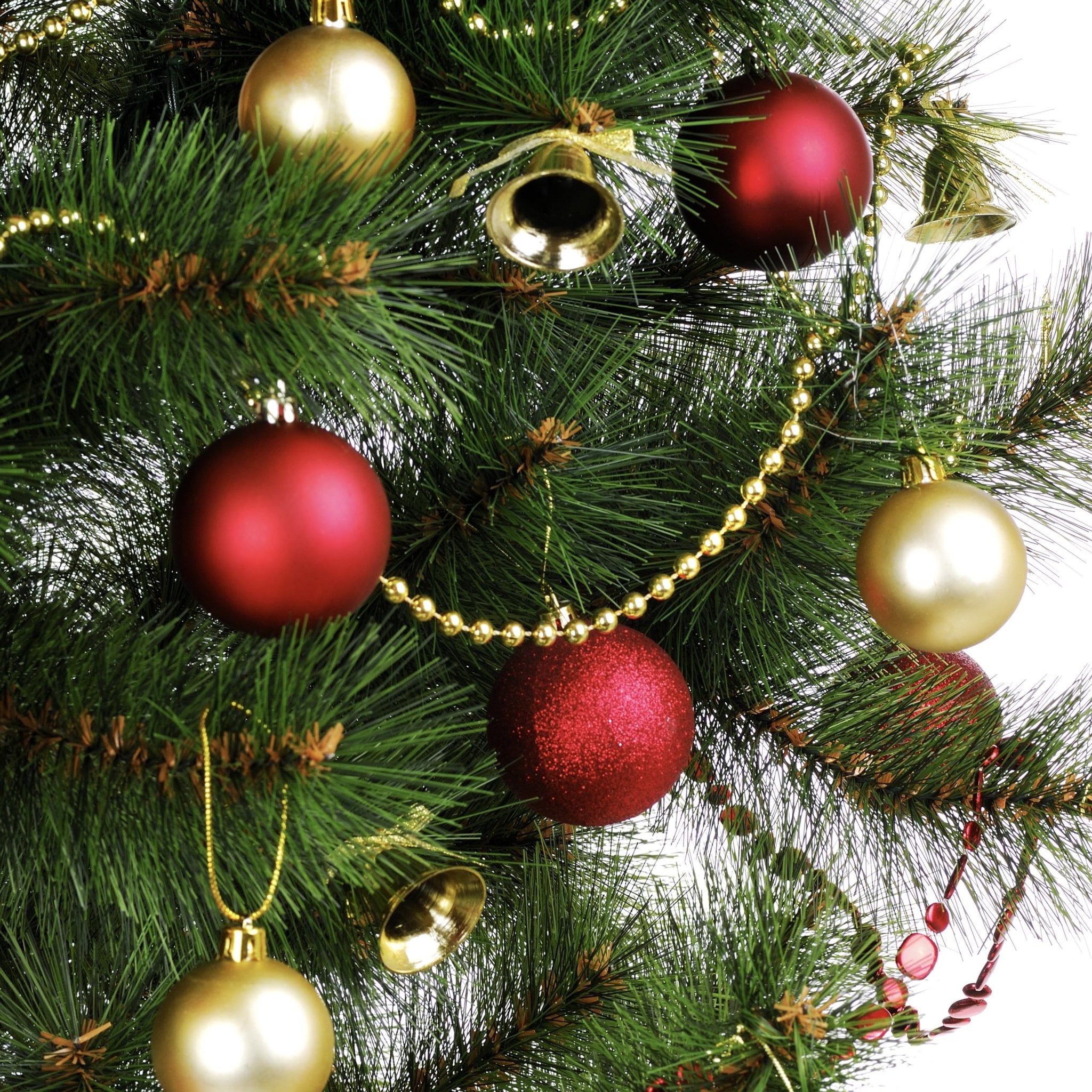 Close-up of a decorated Christmas tree branch with red and gold ornaments, gold bead garland, and small gold bells.