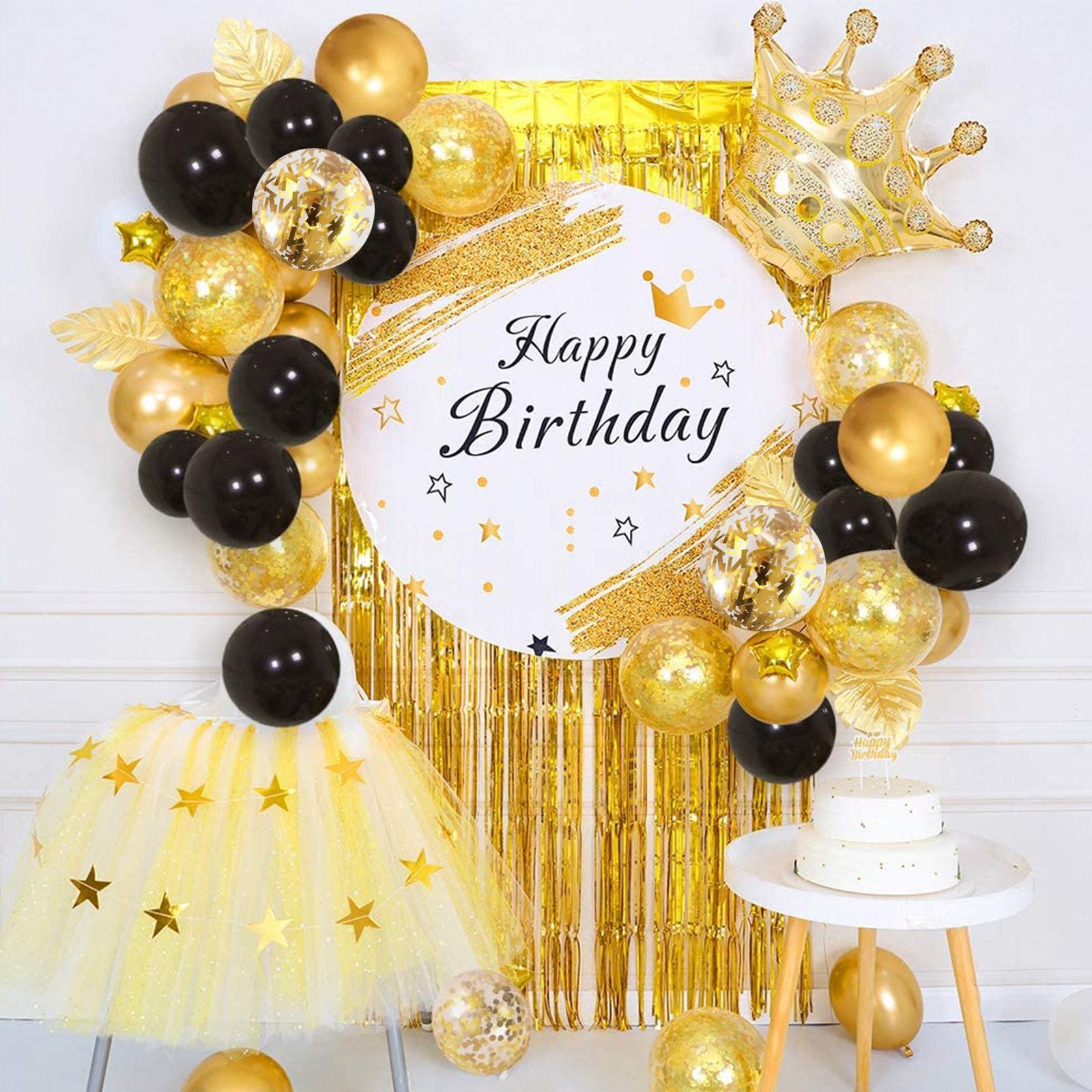 Birthday party balloon arrangement with black, gold, and confetti balloons, a gold crown, and a 'Happy Birthday' sign.