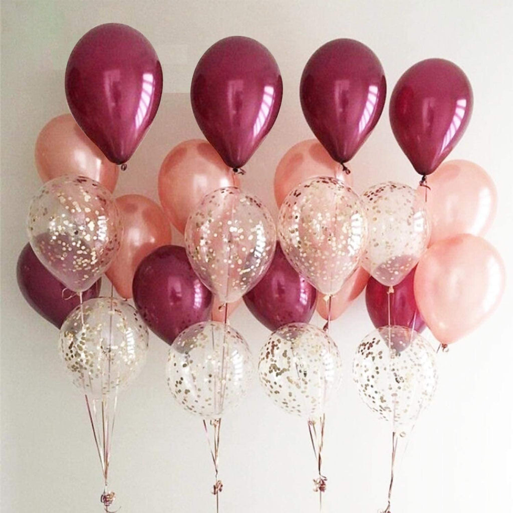 Assortment of burgundy, rose gold, wine red, and confetti latex balloons arranged against a white background.
