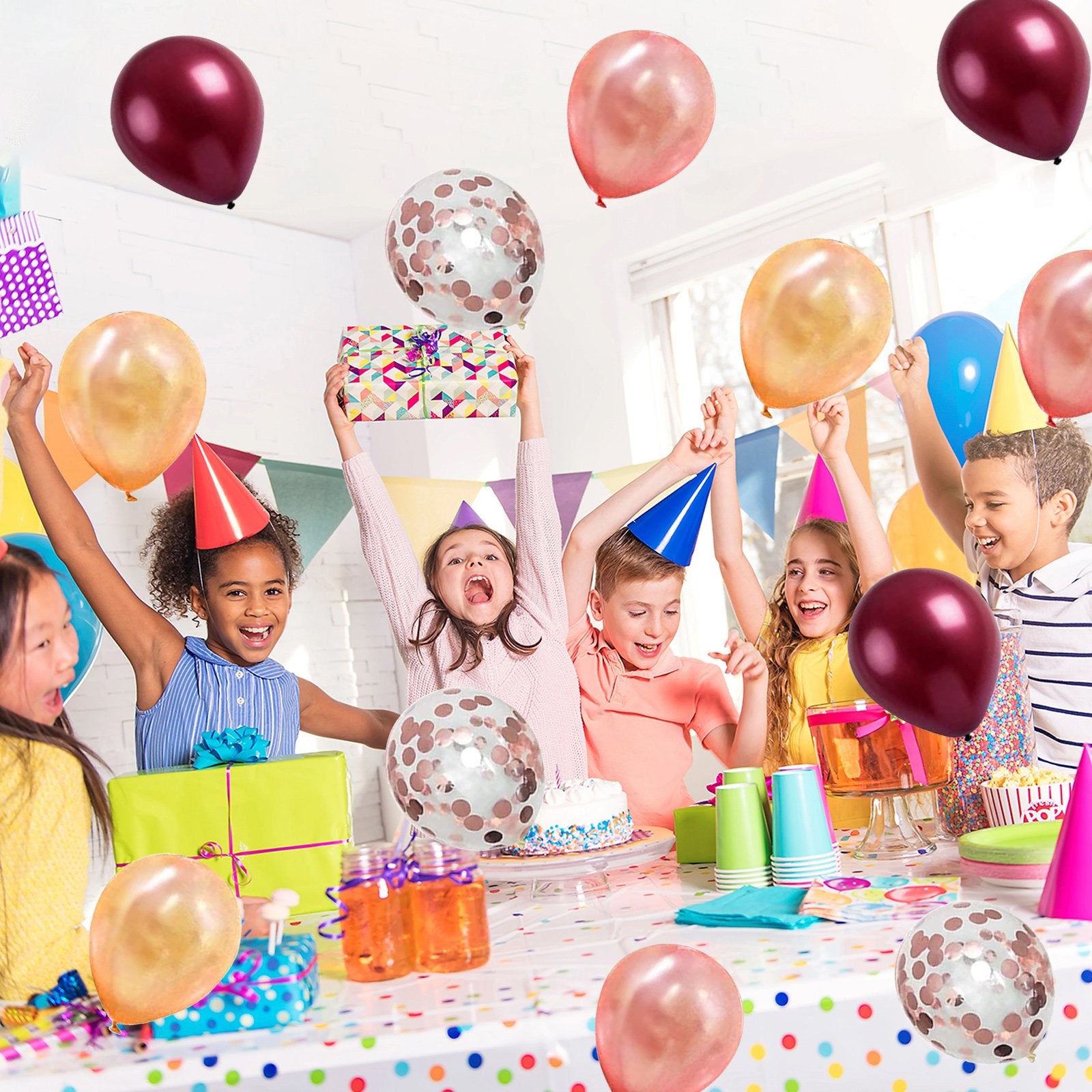 Children celebrating a party with balloons and gifts, some holding presents above their heads.