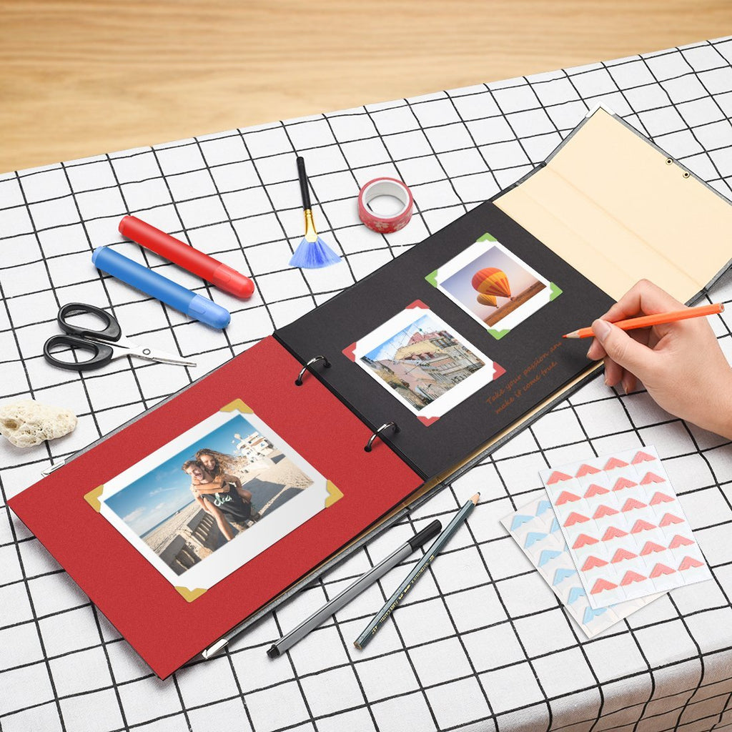 DIY scrapbook album with black pages being filled with photos and art supplies