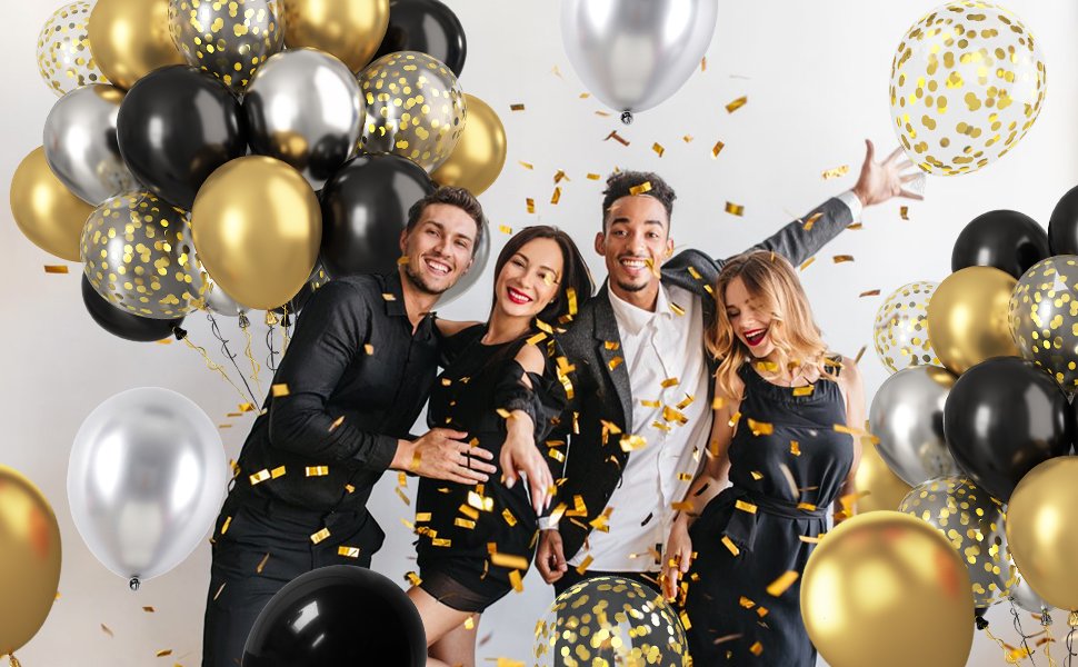 Four people celebrating with black, gold, and silver balloons and confetti