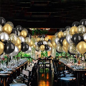 Party balloons in black, gold, silver, and confetti designs arranged above a formal dining table setting.
