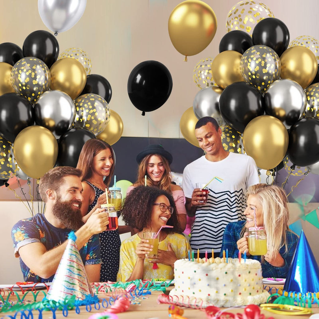 Group of friends celebrating with cake and balloons, black, gold, silver, and confetti balloons fill the scene.