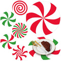 Christmas candy paper round placemats in red and green swirls and stripes, one shown under a plate with steak and cutlery
