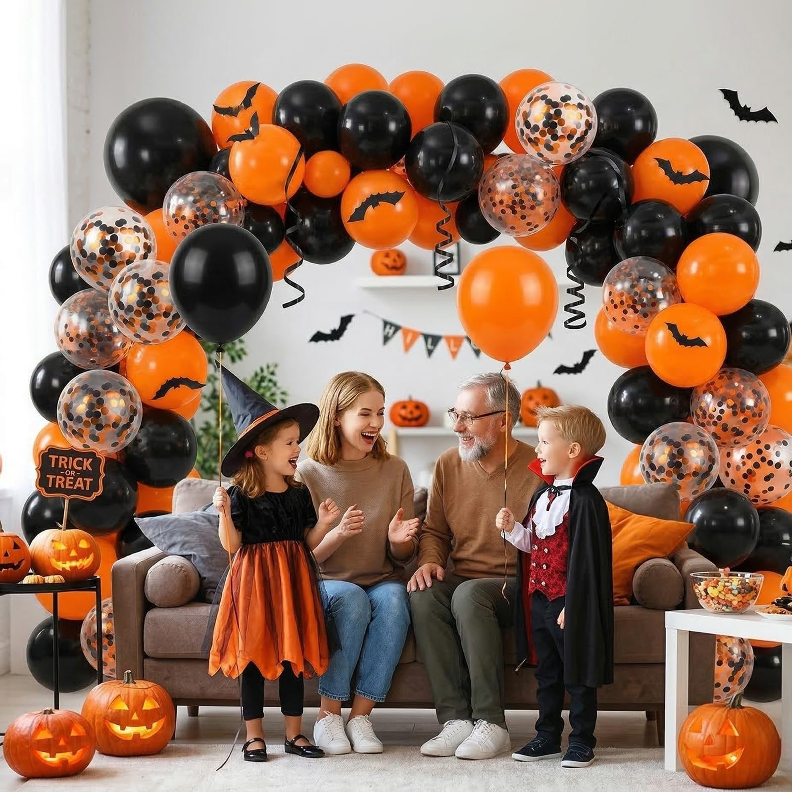Family celebrating Halloween with black, orange, and confetti balloons, pumpkins, and decorations.