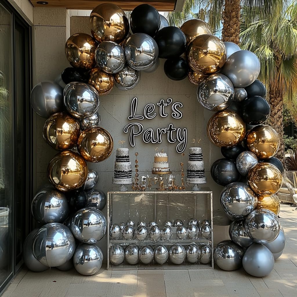 Balloon arch with black, silver, and gold balloons framing a table with cakes and a 'Let's Party' sign.