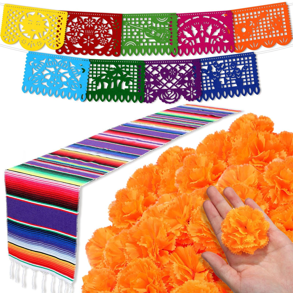 Day of the Dead decoration set with colorful papel picado banners, striped table runner, and orange marigold flowers held in a hand.