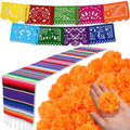 Day of the Dead decoration set with colorful papel picado banners, striped table runner, and orange marigold flowers held in a hand.