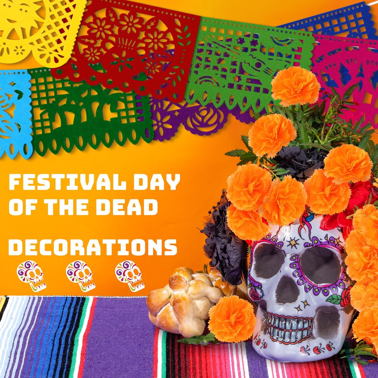 Day of the Dead decorations including papel picado banners, marigold flowers, a decorated skull, and pan de muerto bread on a striped blanket.