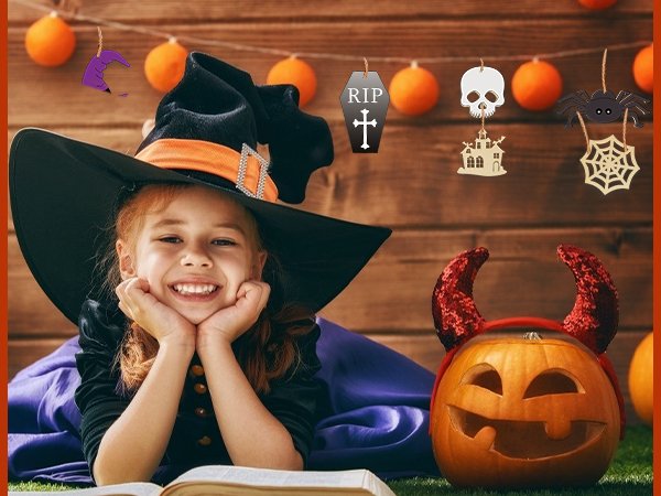 Smiling girl in witch hat with Halloween decorations and carved pumpkin